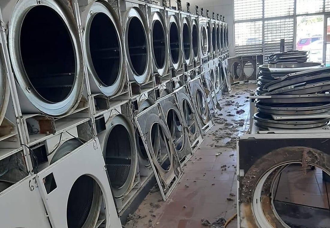 A row of commercial dryers being serviced at a laundromat